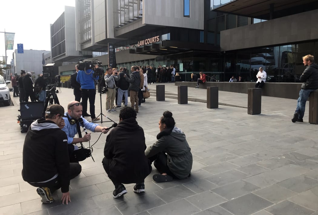 RNZ senior producer Justin Gregory (kneeling, with microphone) talks to victims families in front of the Justice Precinct in Christchurch.