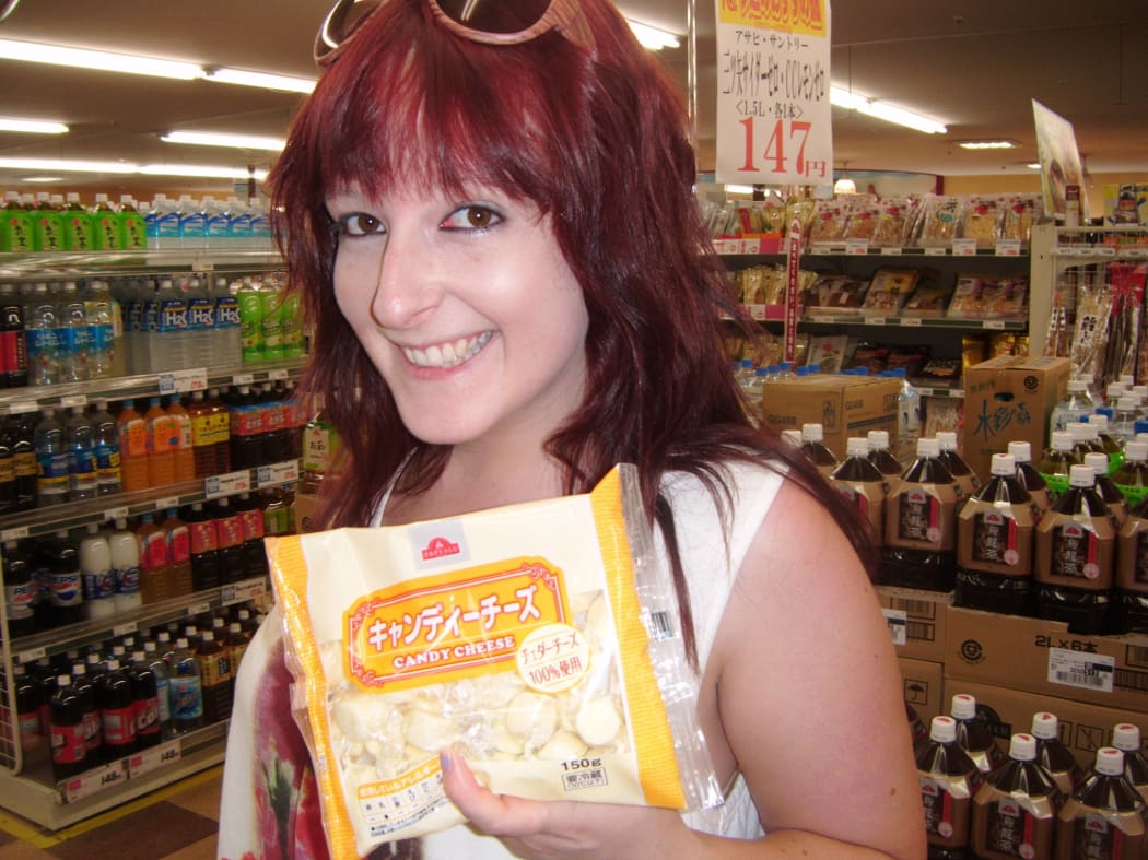 Scarlett, in a market, holding a package of "candy cheese"