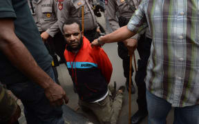 A Papuan pro-independence demonstrator is arrested by police in Jakarta on December 1, 2015 after police fired tear gas at a hundreds-strong crowd hurling rocks during a protest against Indonesian rule over the eastern region of Papua.