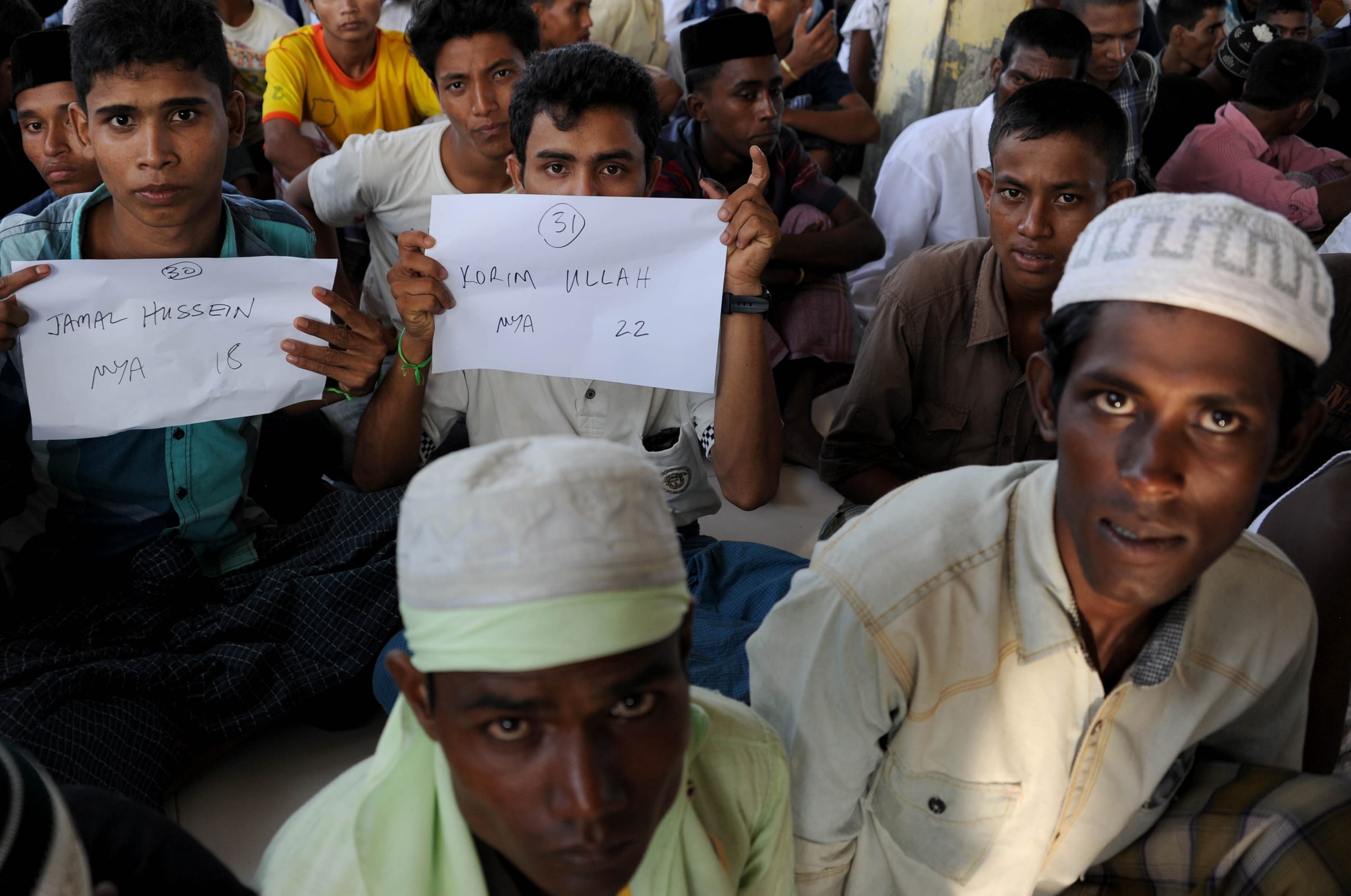 Rescued Myanmarese, part of a group of mostly Rohingyas from Myanmar and Bangladesh, prepare for a photographic identification procedure by an Indonesian immigration official in Aceh.