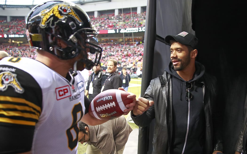 Seattle Seahawks quarterback Russell Wilson wishes Jeremiah Masoli of the Hamilton Tiger-Cats good luck before a match.