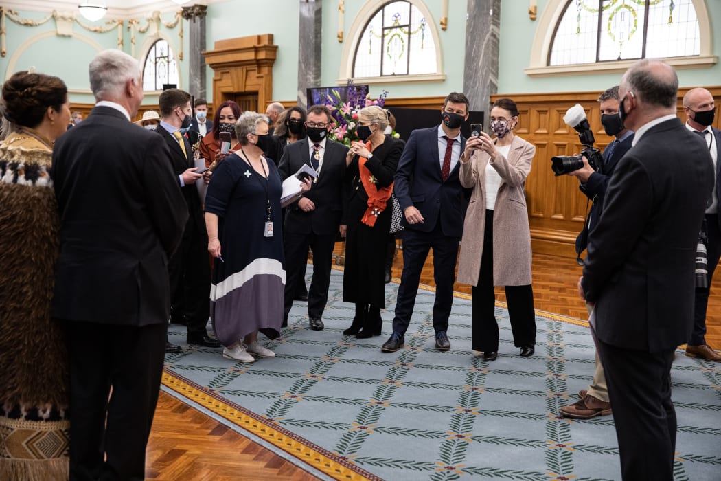 The Prime Minister, Jacinda Ardern snaps a quick photo on her cellphone before joining Cindy Kiro and her husband Dr Davies for an official portrait