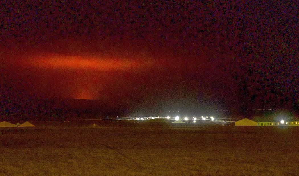 The red shimmer from magma is seen coming out from the erupting Fagradalsfjall volcano behind the town of Keflavik, in Iceland.