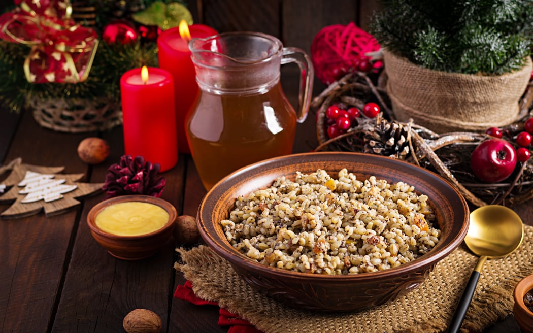 A bowl of grains in front of a jar filled with honey. A Christmas tree is in the background.
