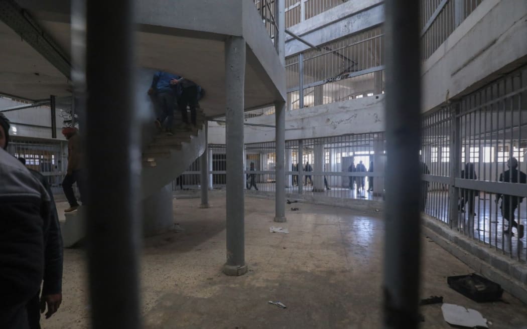 People walk inside the notorious Sednaya prison as Syrian rescuers search for potential hidden basements at the facility in Damascus on 9 December, 2024.