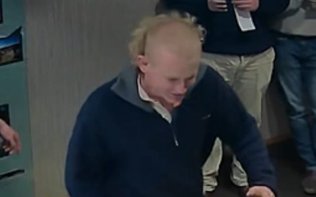 A man with blonde hair, light skin tone, wearing a navy blue jacket.