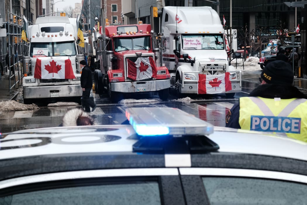 People walk near Canadian Parliament buildings as hundreds of truck drivers and their supporters gather to block the streets of downtown Ottawa as part of a convoy of truck protesters against Covid mandates.