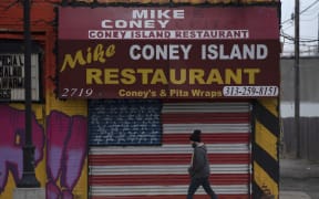 A man passes a closed restaurant near the Eastern Markets in Detroit, Michigan on 24 March 2020.