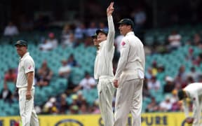 Australian captain Steve Smith (C) looks at the weather with team-mates Adam Voges (R) and David Warner (L) as rain delays the match against the West Indies on the second day of the third Test in Sydney on January 4, 2016. AFP PHOTO / William WEST