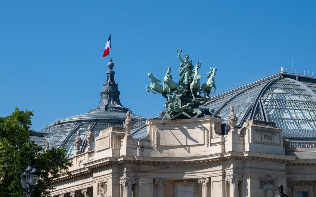 Immortality outpacing Time (L'Immortalite devan?ant le Temps) is an allegorical Baroque style sculpture on the corner of the roof of the Grand Palais de Paris, on the Avenue des Champs-Elysees side in Paris, France, June 25, 2024. Tricolor flag blue white red. (Photo by Riccardo Milani / Hans Lucas / Hans Lucas via AFP)