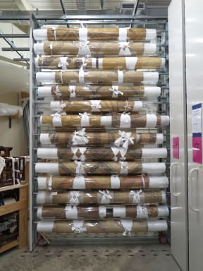 Rolled whāriki (mats) in storage with new see through coverings.