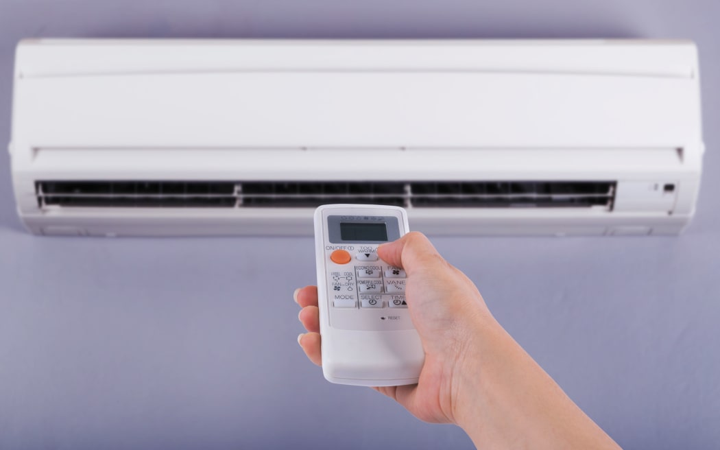 Hand holding remote control directed on the air conditioner