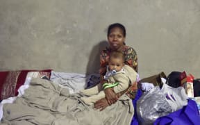 A woman and her baby take at a temporary cyclone shelter in the town of Ayr in far north Queensland.