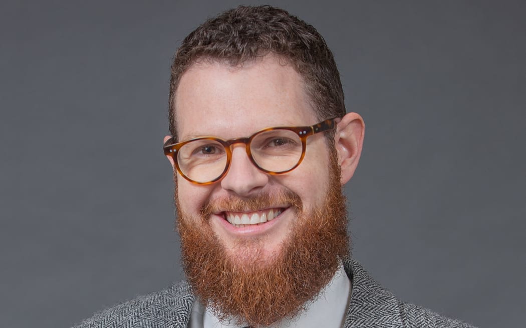 Craig McCulloch smiling wearing a suit and glasses