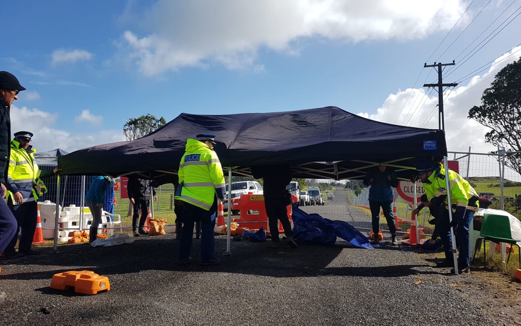 Police officers helping set up a marquee for occupiers to sit under at the frontline in Ihumātao, South Auckland