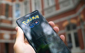A person holding a phone playing Pokemon Go in a street.