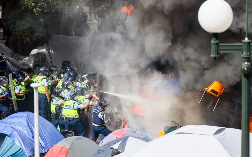 A chair flies through smoke from a fire lit in front of the police while they try to extinguish the blaze