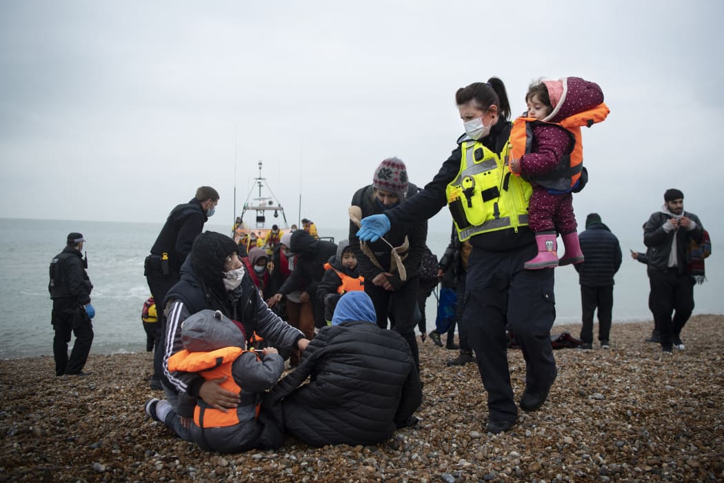 A member of the UK Border Force helps child migrants on a beach in Dungeness, on the south-east coast of England, on November 24, 2021 after being rescued while crossing the English Channel.