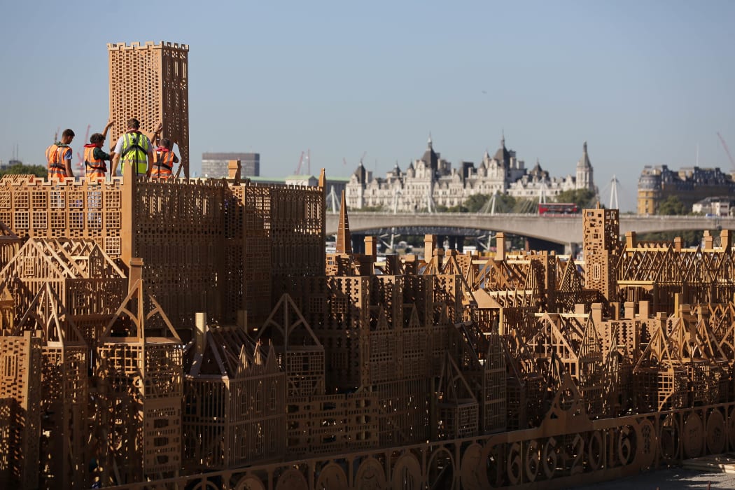 The final touches are made to the 120m-long wooden sculpture on 30 August as it is moored on the Thames.