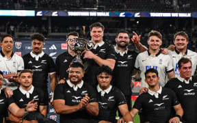 Scott Barrett holds the trophy as New Zealand All Blacks team celebrates.