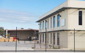 Modern office building with industrial warehouse and workshop  on the rear plan.