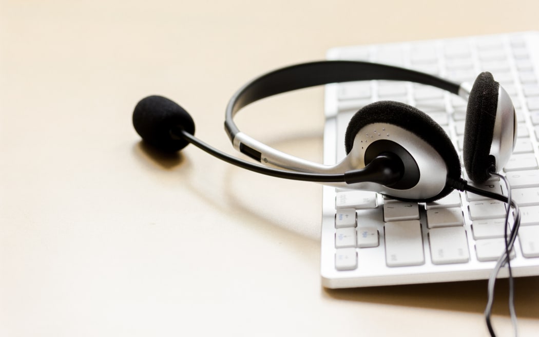 Call center support table with headset and keyboard set on beige background