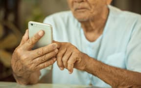 Happy asian senior man using the mobile phone at home