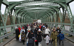 Ukrainian refugees walk a bridge at the buffer zone with the border with Poland in the border crossing of Zosin-Ustyluh, western Ukraine on 6 March, 2022.