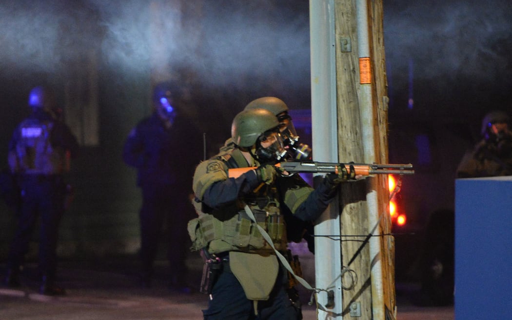 A state trooper aims his gun at protesters in Ferguson, Missouri, on 25 November, 2014 during a demonstration a day after violent protests and looting following the grand jury decision in the fatal shooting of  Michael Brown.