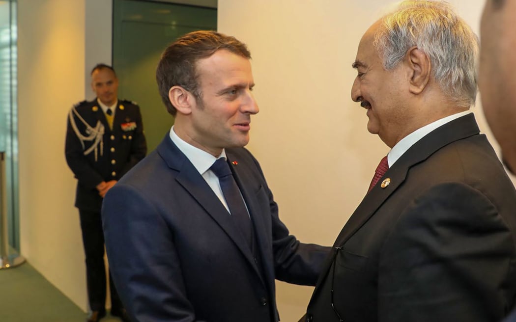 This image grab taken from a video obtained from the Libyan strongman Khalifa Haftar's self-proclaimed Libyan National Army War Information Division's Facebook page on January 19, 2020, shows Haftar (2nd-R) greeting with French President Emmanuel Macron (C) in the German capital Berlin.