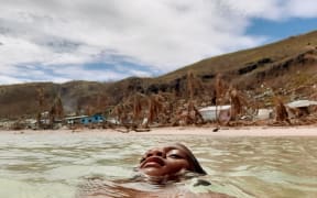Ten year old Epineri Lata takes a dip in the ocean to escape the intense heat on the island of Kia in Fiji. In the background is the visible evidence of cyclone damage to the island.