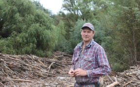Tim Jefferd standing at the wall of wood on his farm boundary.
