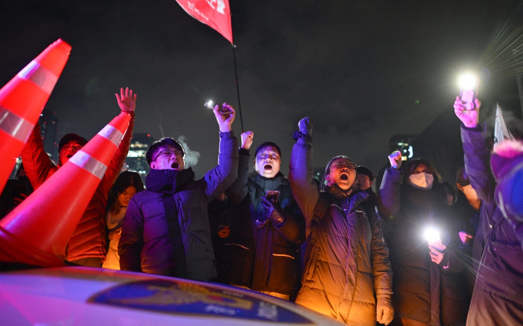 People gesture as they gather outside the National Assembly in Seoul on December 4, 2024, after South Korea President Yoon Suk Yeol declared martial law. - South Korea's President Yoon Suk Yeol on December 3 declared martial law, accusing the opposition of being "anti-state forces" and saying he was acting to protect the country from "threats" posed by the North. (Photo by Anthony WALLACE / AFP)
