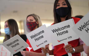Qantas staff welcome the passengers of Los Angeles flight at the arrival gates of the Sydney International airport on November 1, 2021.