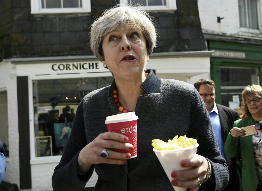 FILE - In this May 2, 2017 file photo Britain's Prime Minister Theresa May having some chips while on a walkabout during a election campaign stop in Mevagissey, Cornwall.