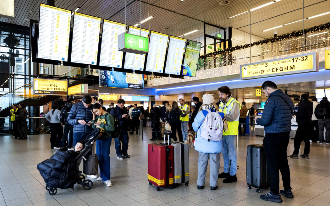 Staff members in yellow jackets assist travellers at Schiphol Airport at Amsterdam Schiphol airport, where snow prompts over 700 flight cancellations on January 7, 2026. (Photo by Robin van Lonkhuijsen / ANP / AFP) / Netherlands OUT / NETHERLANDS OUT / NETHERLANDS OUT