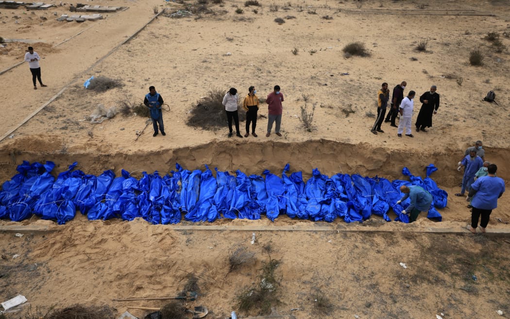 Palestinians bury bodies in a mass grave in Khan Yunis cemetery, in the southern Gaza Strip on November 22, 2023, amid ongoing battles between Israel and the Palestinian Hamas movement. The remains, which bore only numbers, had come from the Indonesian and Al-Shifa hospitals in the northern Gaza Strip, according to members of the committee at the burial site.