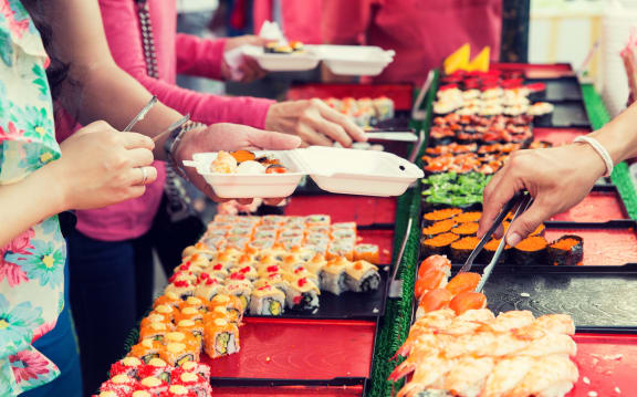 cooking, asian kitchen, sale and food concept - close up of hands with tongs taking sushi at street market