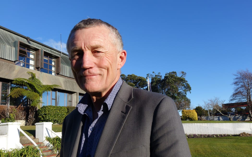 Man stands outside offices under  blue sky