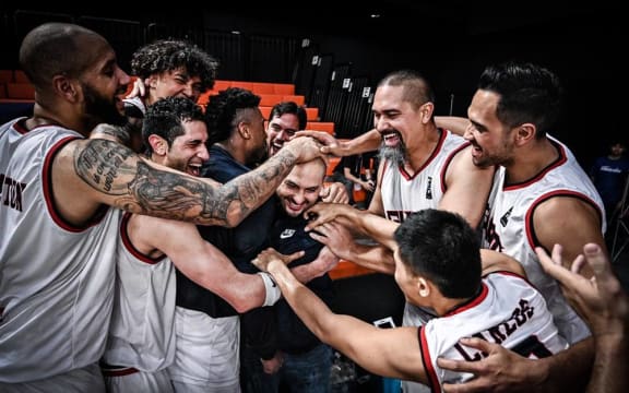 Guam's players embrace coach EJ Calvo after winning the FIBA Asia Cup's Eastern Region Pre-Qualifying tournament.