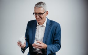 Professor Ian Bissett wears a blue suit and holds a Insides co. device in his hands