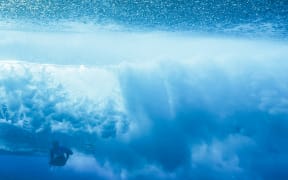 New Zealand's Billy Stairmand duck dives a wave in the 5th heat of the men's surfing round 1, during the Paris 2024 Olympic Games, in Teahupo'o, on the French Polynesian Island of Tahiti, on July 27, 2024.