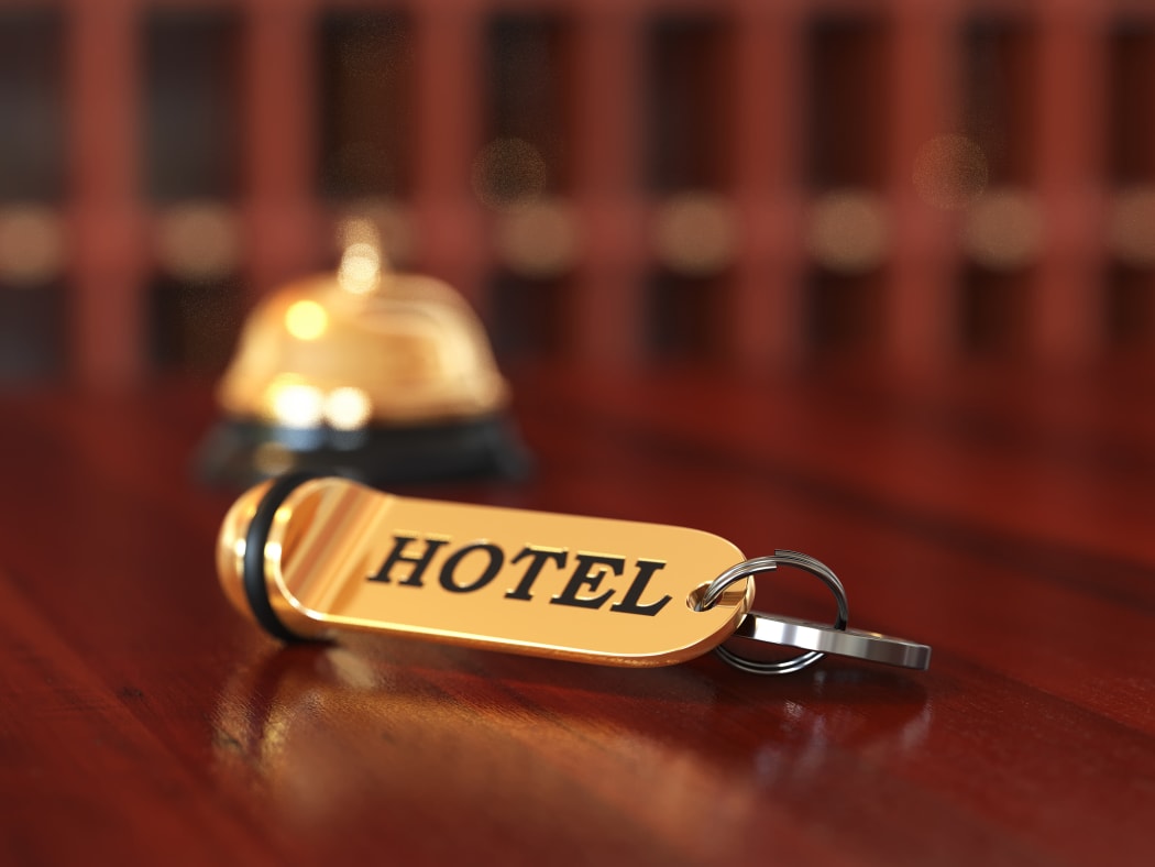 Close up of room access key and bell on wooden reception desk. Soft focus illustration