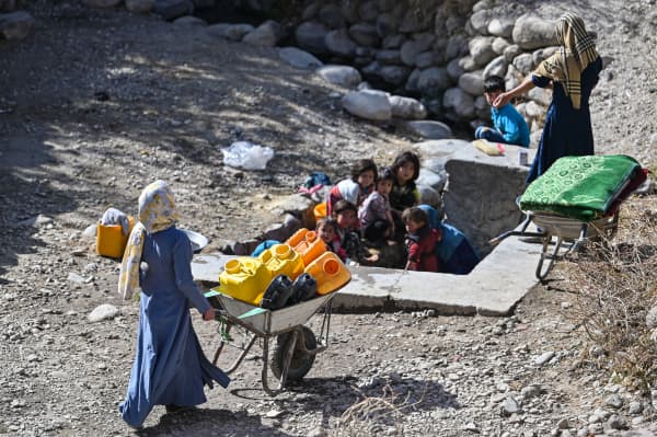 An Afghan woman carries a wheelbarrow while going for water to a fountain in a village in Qarabagh district distant 56 km to the south-west of Ghazni, in Ghazni province, on 14 November, 2021.