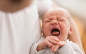 Crying baby in mother's arms.