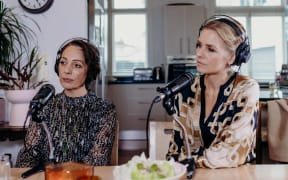 Annabelle Lee-Mather (left) and Mihingarangi Forbes (right) sit with headphones on in front of microphones for the podcast re_covering.