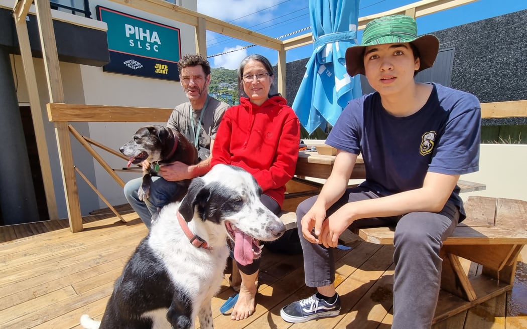 Steve Morrison, Anne Bilek and their son Edmund Morrison at the Piha Surf Club with dogs Helen Clark and Bella (front)