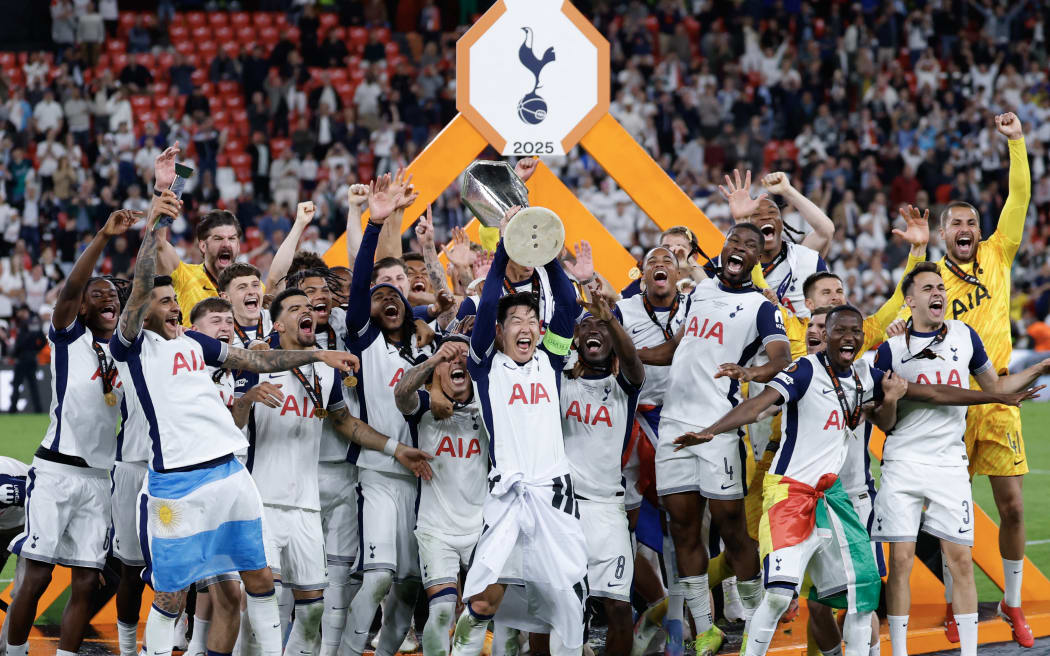 Tottenham Hotspur's South Korean forward Son Heung-min raises the trophy as he celebrates with teammates winning the UEFA Europa League final 1-0 over Manchester United, Bilbao, 2025.