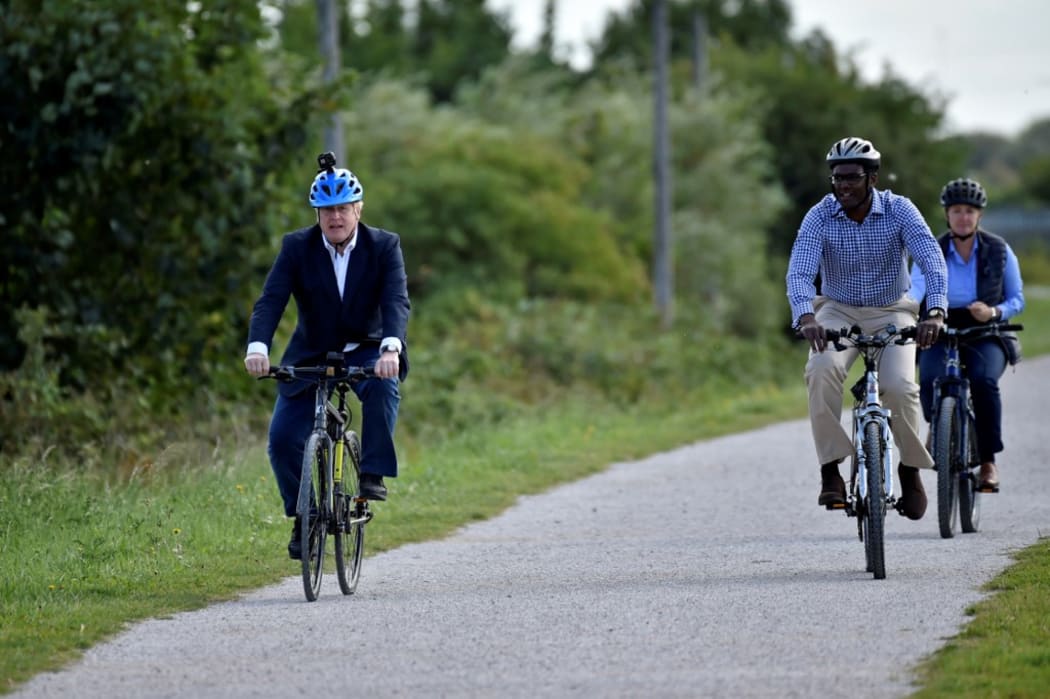 Britain's Prime Minister Boris Johnson (L) and Conservative MP for Broxtowe Darren Henry ride bicycles at the Canal Side Heritage Centre in Beeston.