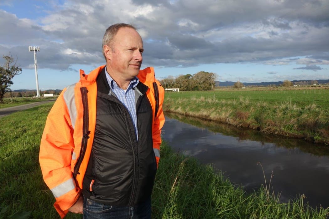 Brendon Love, the clean-up project manager at the Kopepepo Canal. Wearing a high-vis jacket he stands on the banks of the canal on a cloudy day